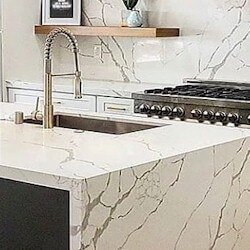 Radiant bright white background with gray, dynamic brown-grey veining kitchen island with waterfall.