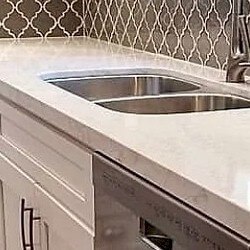 White background with bold, dynamic light grey and gold veining countertop with undermount sink.