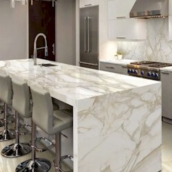 Luminous white background with dynamic light gold and brown veining porcelain island with right side waterfall.